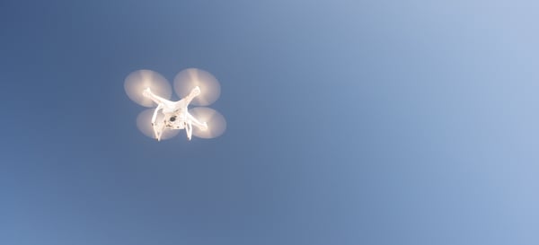 white-uav-quadcopter-drone-in-flight-blue-sky-PX9VCHL